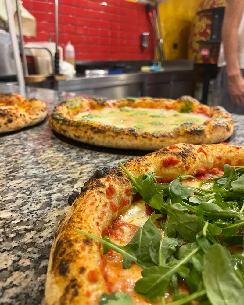 Il banco in granito e le piastrelle rosse della pizzeria, con una pizza alla rucola